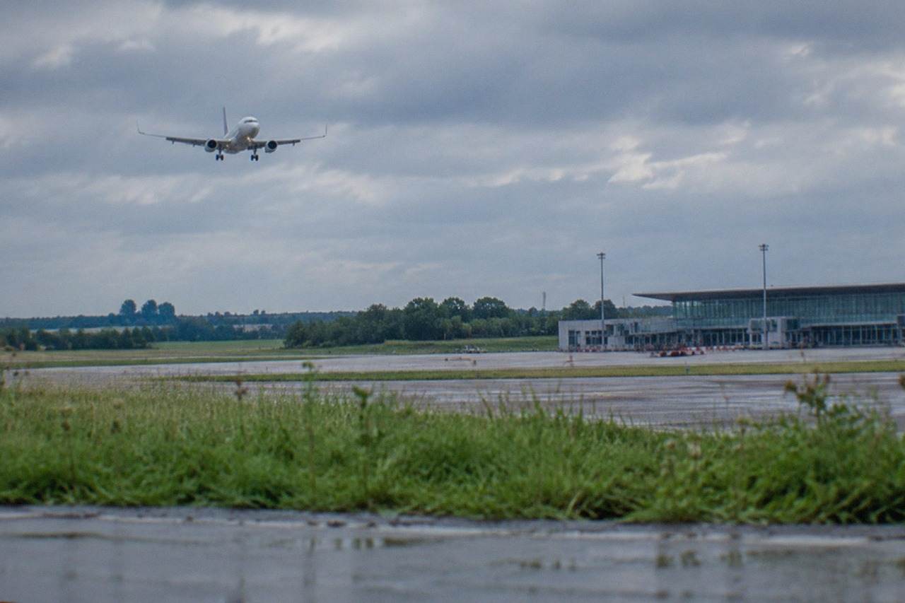 A passenger plane descending over green fields on the approach to Nantes Atlantique airport in western France