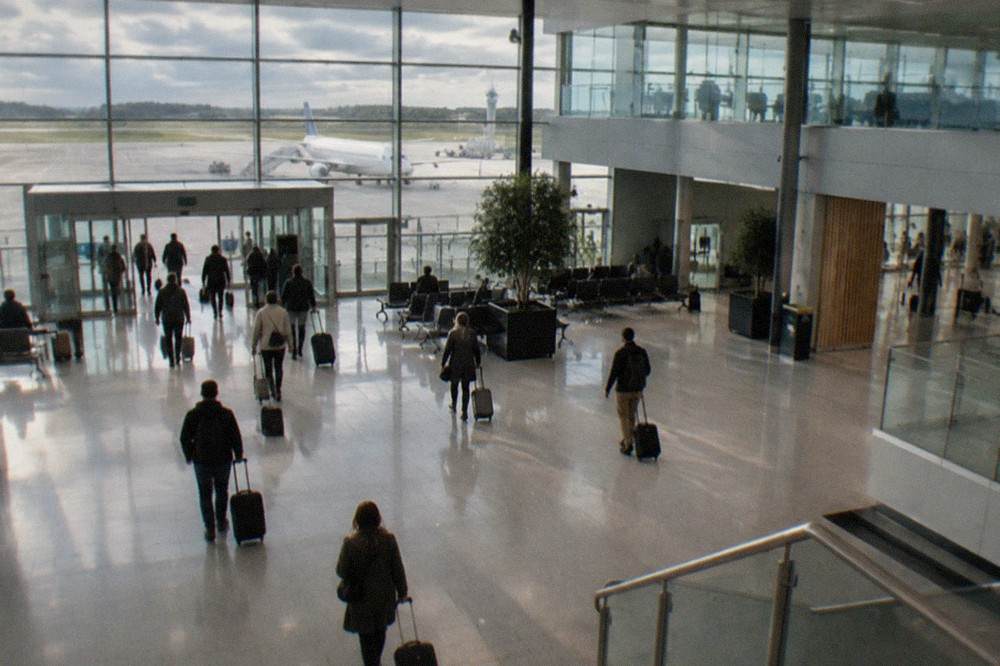Travellers with suitcases walking through the bright arrivals hall of a small French regional airport