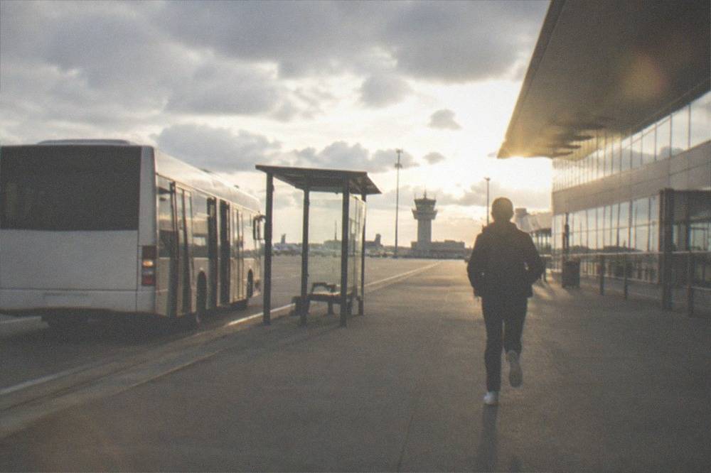 A white airport shuttle bus parked at a stop outside a French regional airport terminal