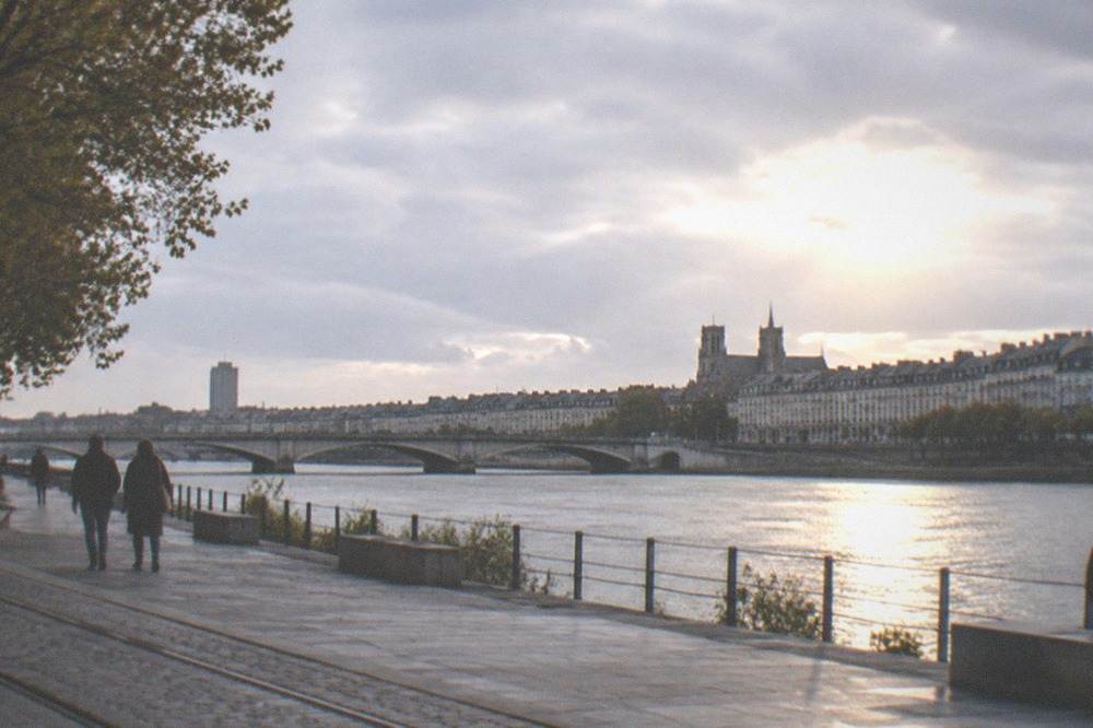 Sunlight over the Loire river in Nantes with the city skyline and a stone bridge in the background