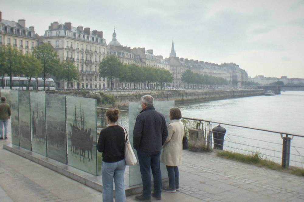 Visitors reading the glass and stone panels of the slavery abolition memorial on the Nantes riverside