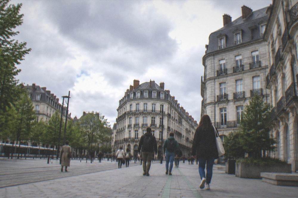 Walkers following a green painted line through a sunlit square in central Nantes