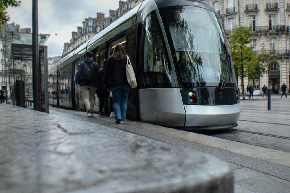 People boarding a tram at a central Nantes stop on a sunny weekend morning