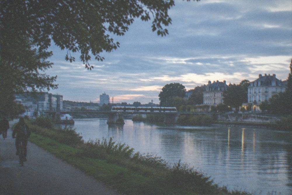 A tram crossing the Loire towards the Île de Nantes with riverside warehouses in view