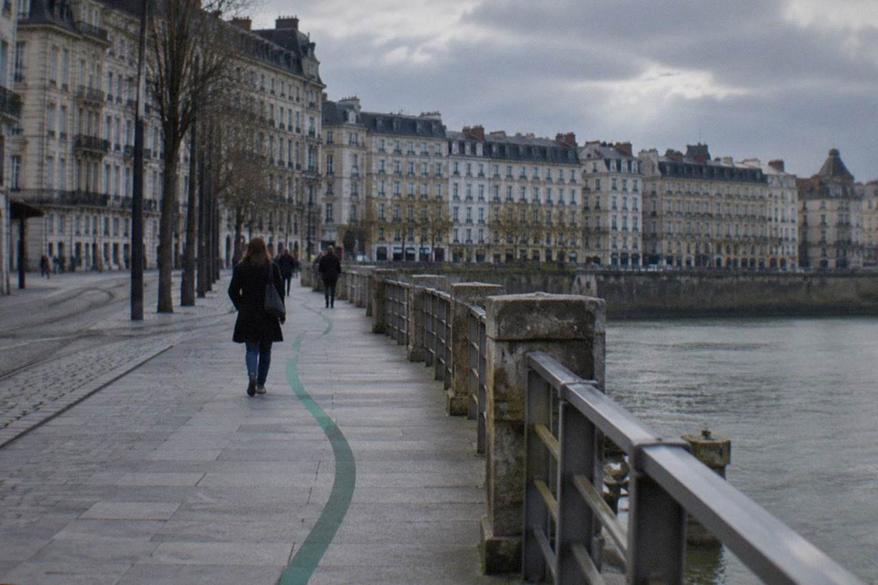 A green painted line curving along a stone pavement beside old Nantes buildings