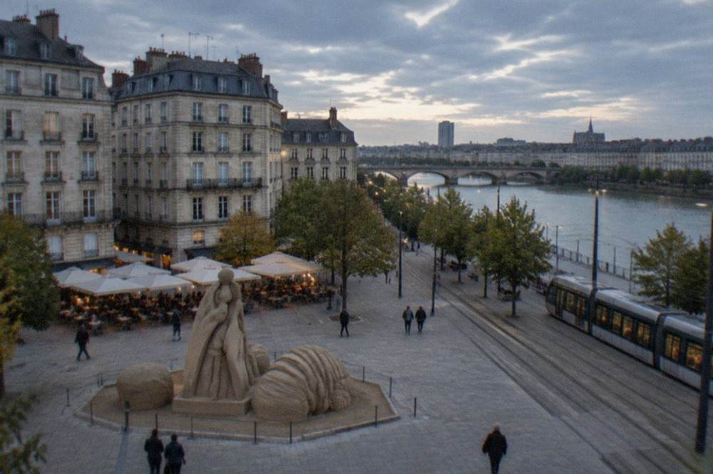 A sand-coloured sculpture installation on a Nantes square with café terraces behind