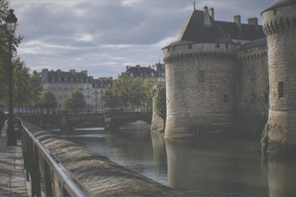 The stone towers and ramparts of a castle in Nantes seen across a moat