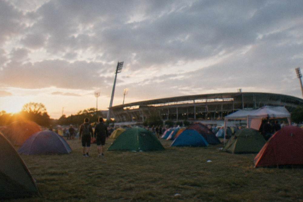 Festival campsite with colourful tents stretching across a field at sunset