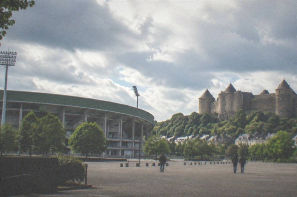 Medieval stone castle with round towers above a small French town and green valley