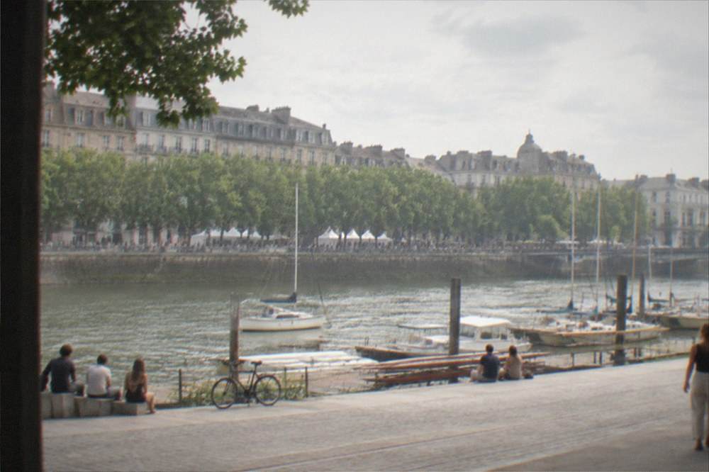 Rowing boats and small yachts moored along a tree-lined river at a summer festival