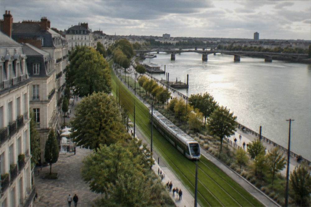 A tram gliding along a grass-covered track beside the Loire through central Nantes