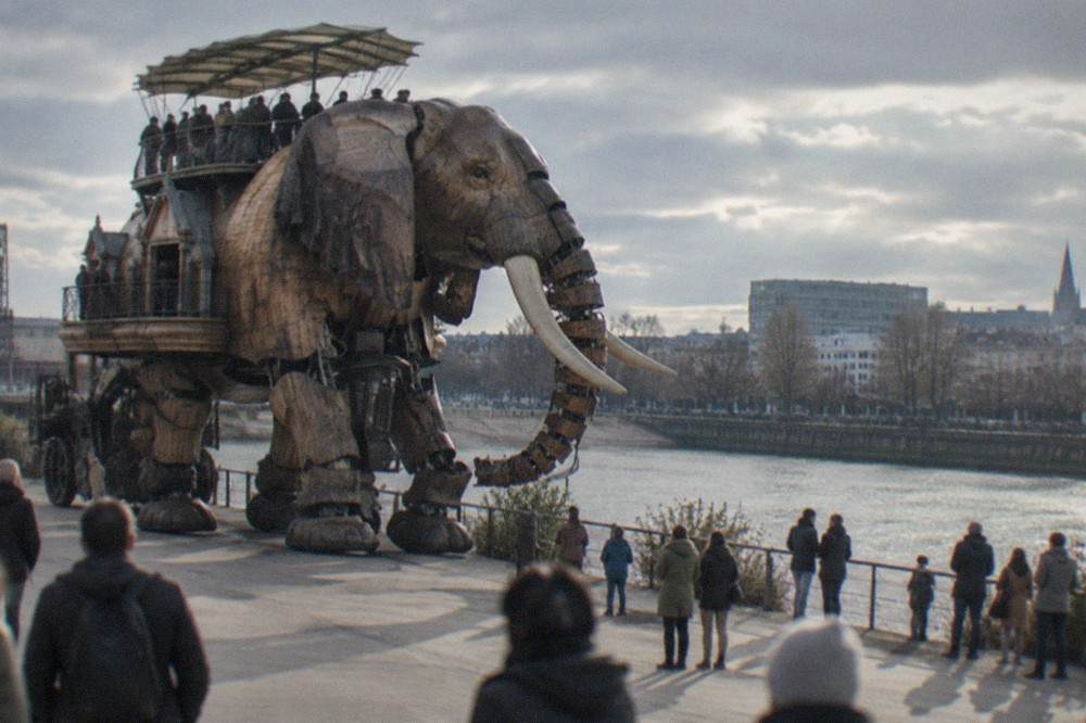 The mechanical Grand Éléphant of Les Machines de l'île walking along the quay on the Île de Nantes with visitors watching