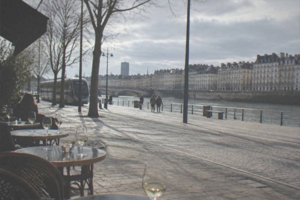 Row of traditional French bistro tables set with glasses of white wine on a terrace in central Nantes