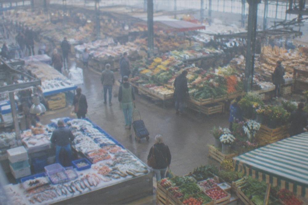 Market stalls with fresh produce, bread and flowers under the canopy of an indoor market hall in Nantes