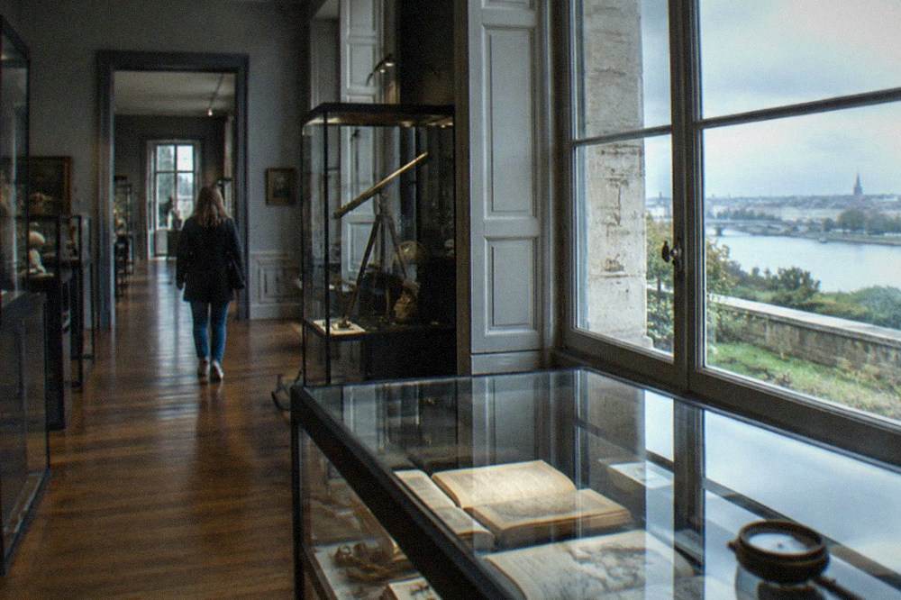 Museum interior with glass display cases of old books and maritime instruments