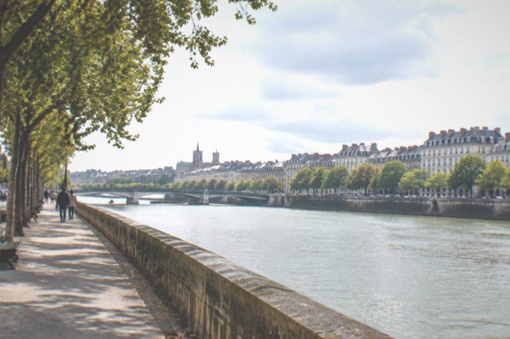 Tree-lined promenade beside the Loire with stone embankments in Nantes