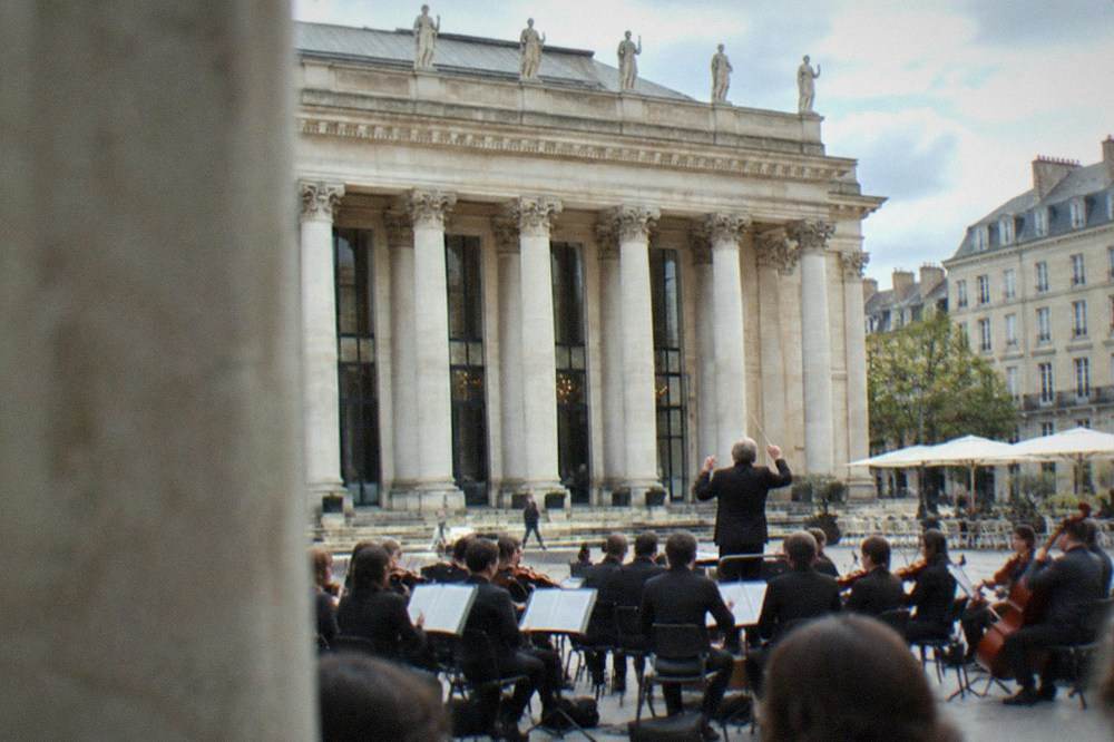 A conductor raising a baton before a full orchestra in rehearsal