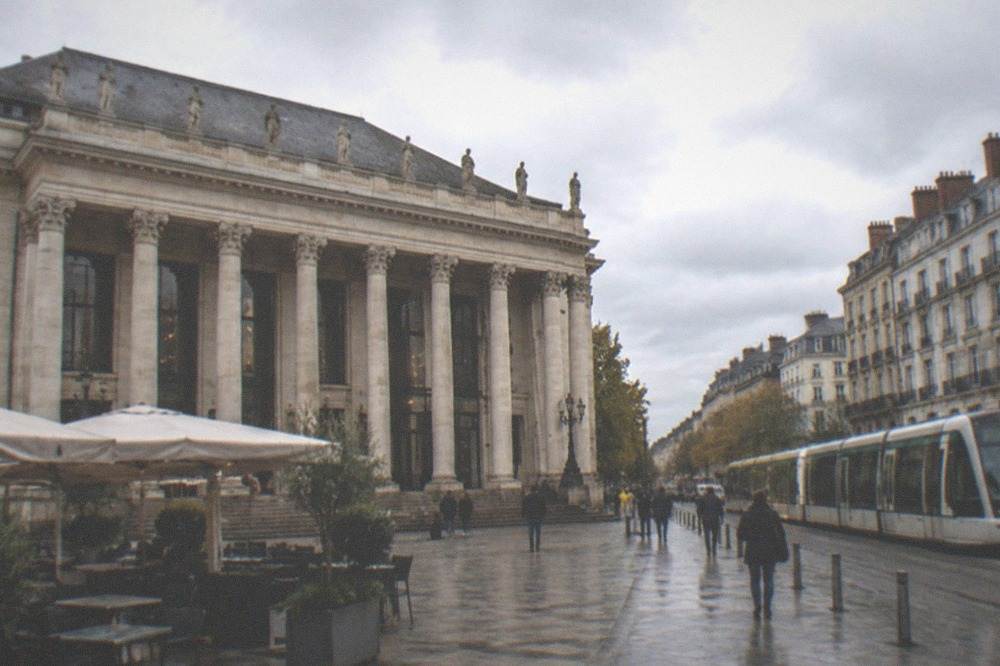 A modern tram gliding along a city street lined with stone buildings