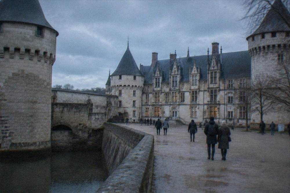 A grand stone castle courtyard with ramparts and visitors strolling beneath grey winter sky