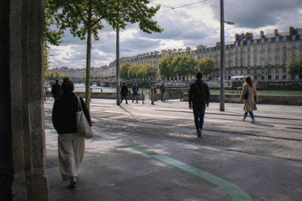 A close view of the green line painted on a Nantes street corner with pedestrians walking past