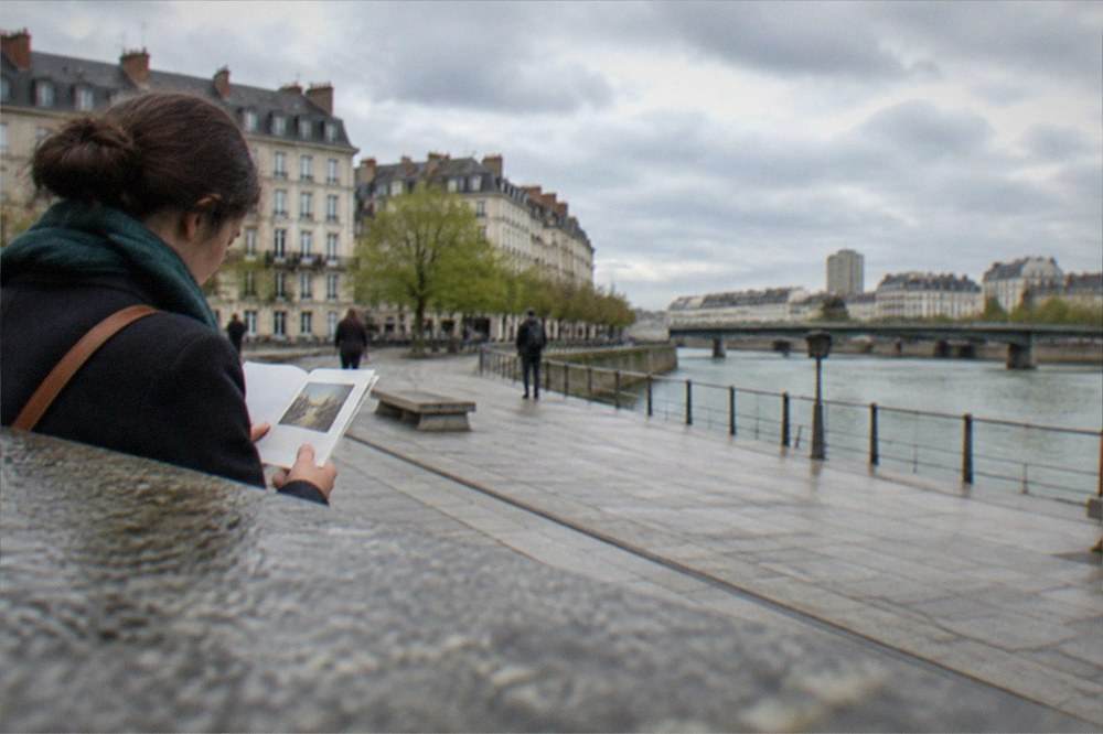 A visitor reading an artwork information sign beside the green line on a Nantes street