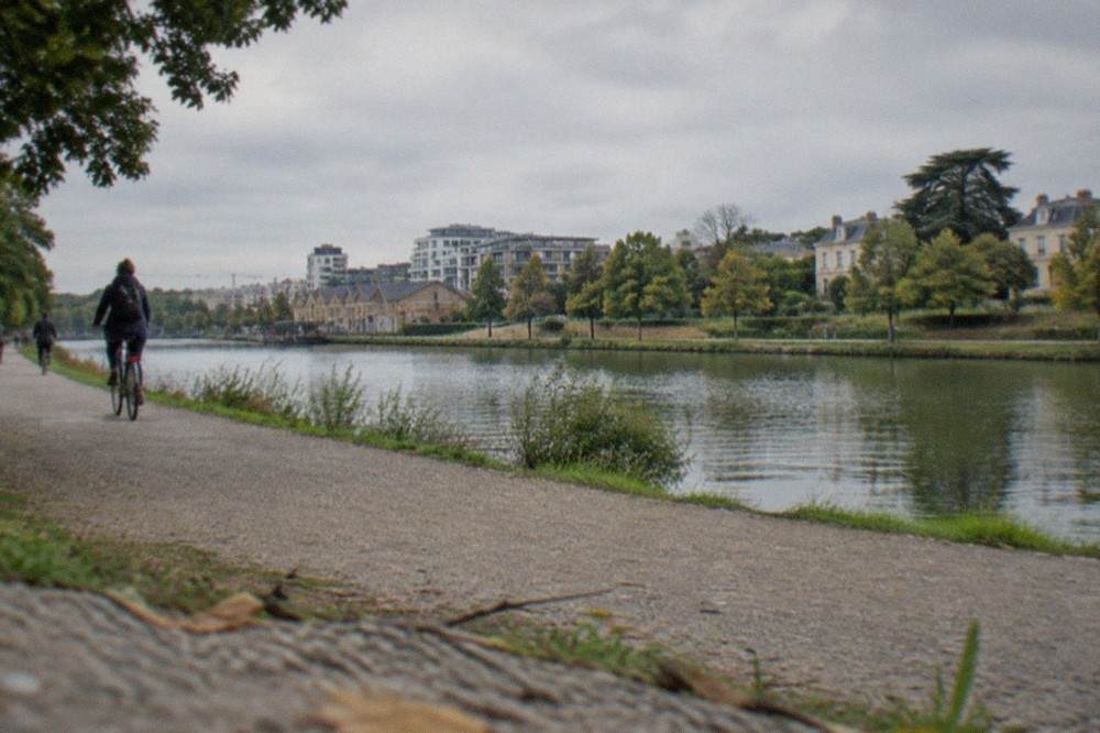 A riverside cycling lane on an island with modern buildings and old warehouse facades behind it