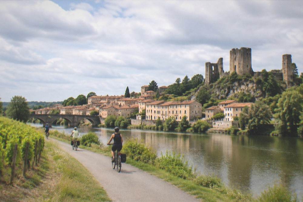 Cyclists on a riverside Loire cycling path passing vineyards near Clisson