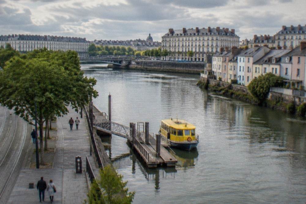 A small yellow river ferry moored at a wooden pontoon beside a row of pastel-coloured fishermen's cottages