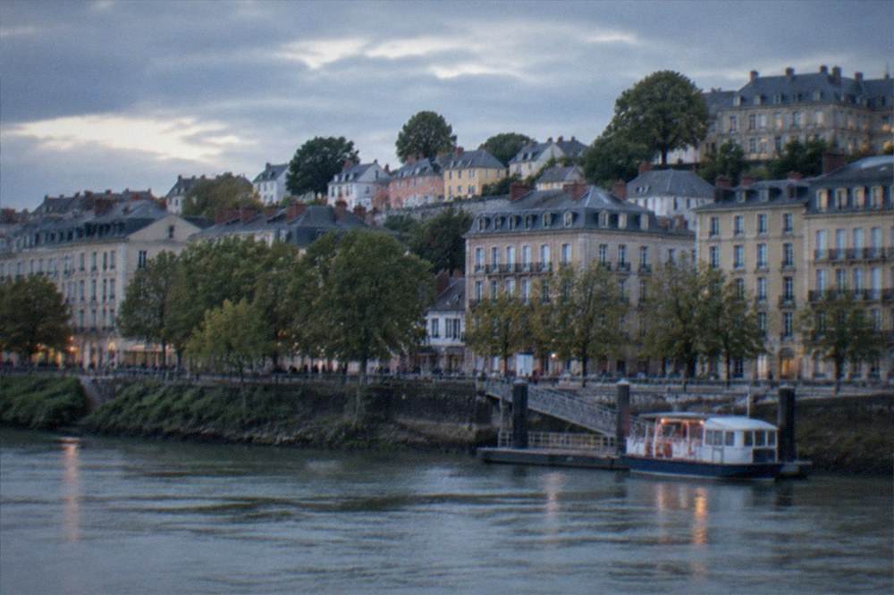 A hillside neighbourhood of small colourful houses above a river landing stage with a small ferry at the pontoon