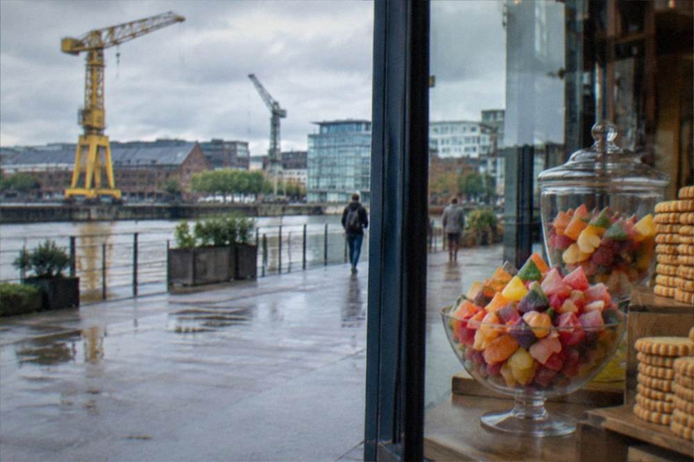 Colourful pyramid-shaped hard candies and stacked butter biscuits displayed together in a confectionery window