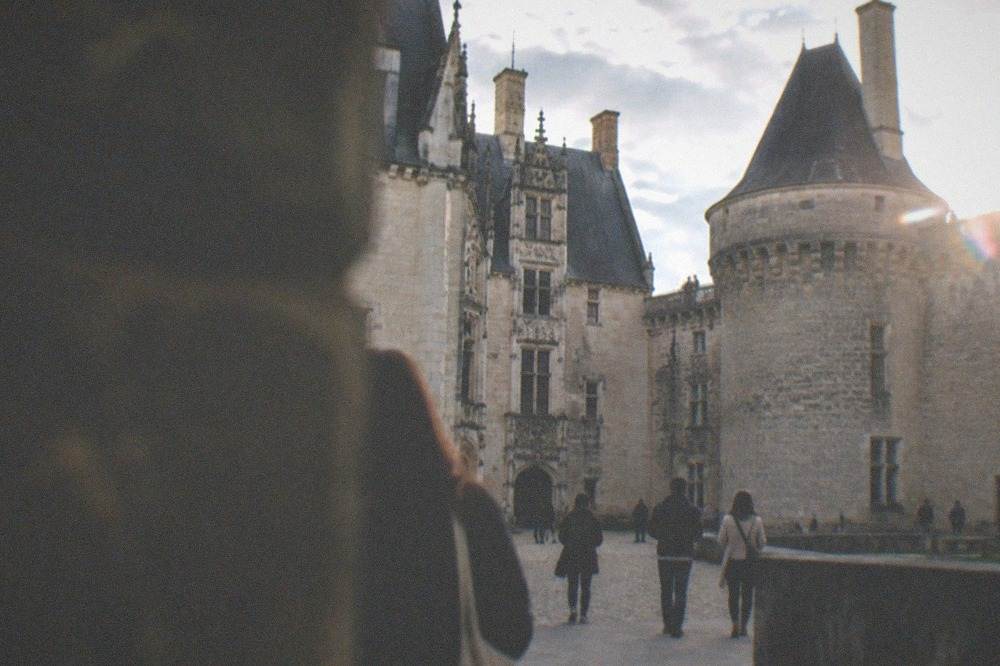 Visitors strolling through a castle courtyard with stone ramparts above