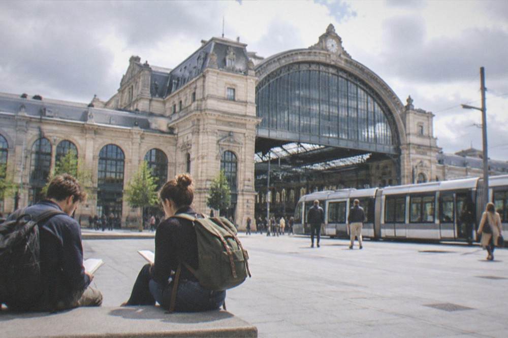 Two travellers with backpacks reading a departure board in a station hall