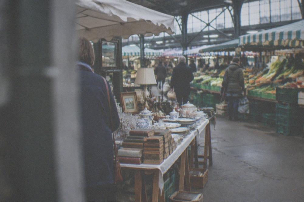 A flea market stall with vintage tableware, old books and bric-a-brac laid out on trestle tables