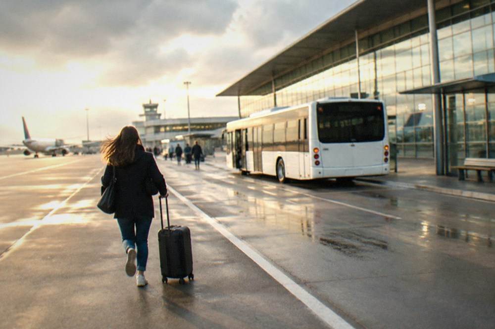 The white airport shuttle bus waiting at a stop outside the terminal