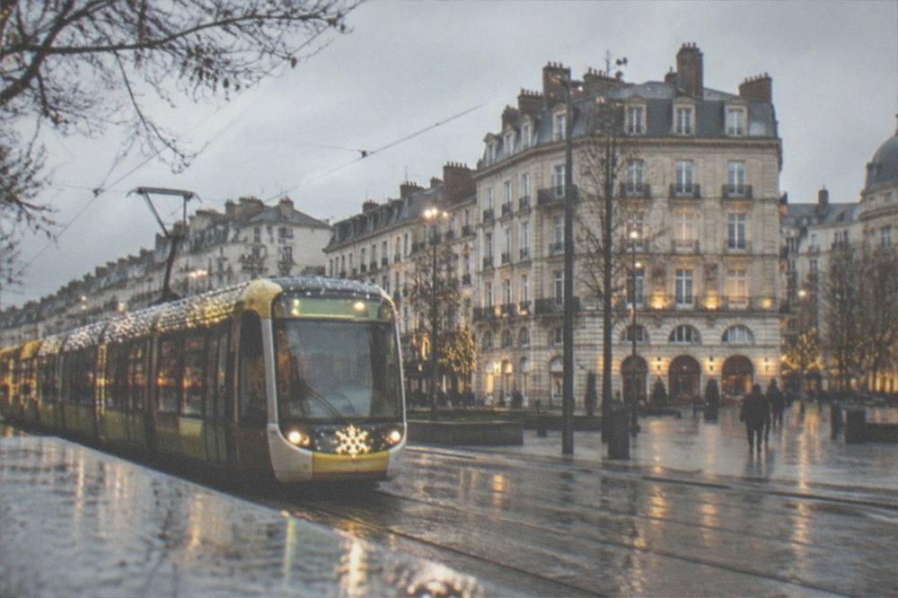 A tram decorated for the festive season passing illuminated buildings in central Nantes