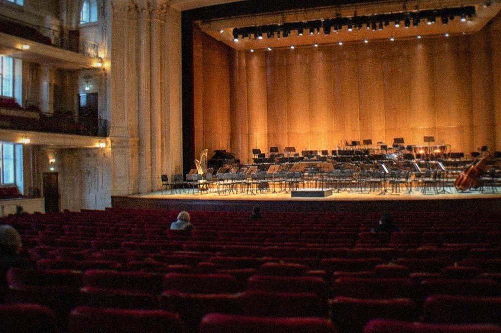 A grand concert hall interior with rows of red seats and a lit stage ready for a classical performance