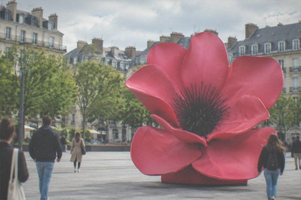 Visitors walking past a large contemporary art installation in a public square in Nantes on a sunny day