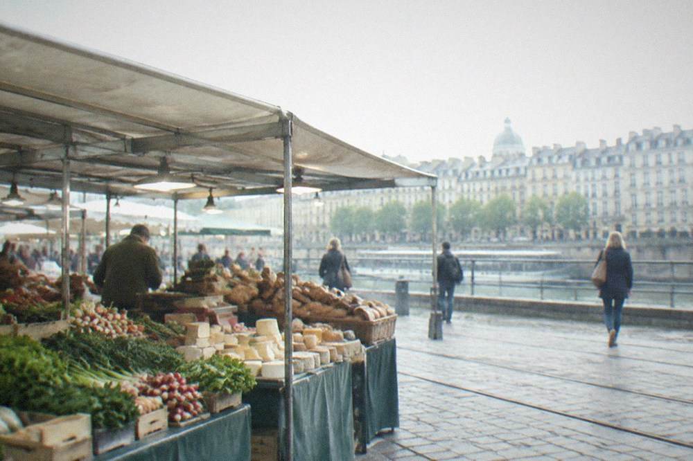 A busy covered food market stall with vegetables, cheese and bread in Nantes