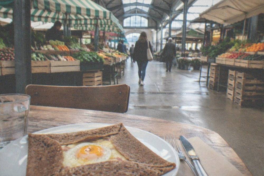 A buckwheat galette with egg and cheese being served at a crêperie table