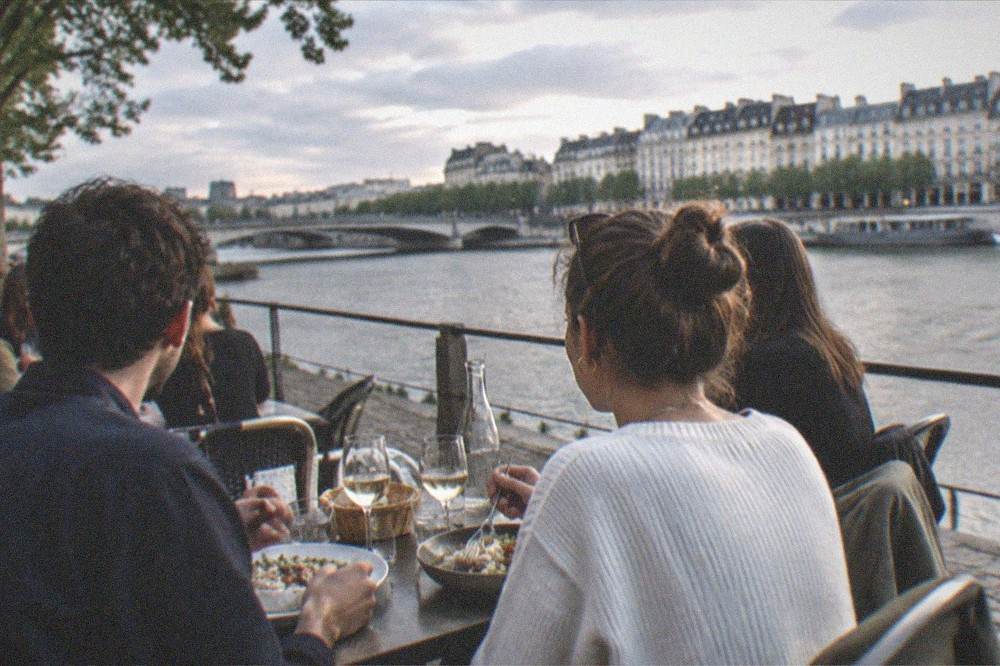 People eating at a terrace table beside the river on a warm evening in Nantes