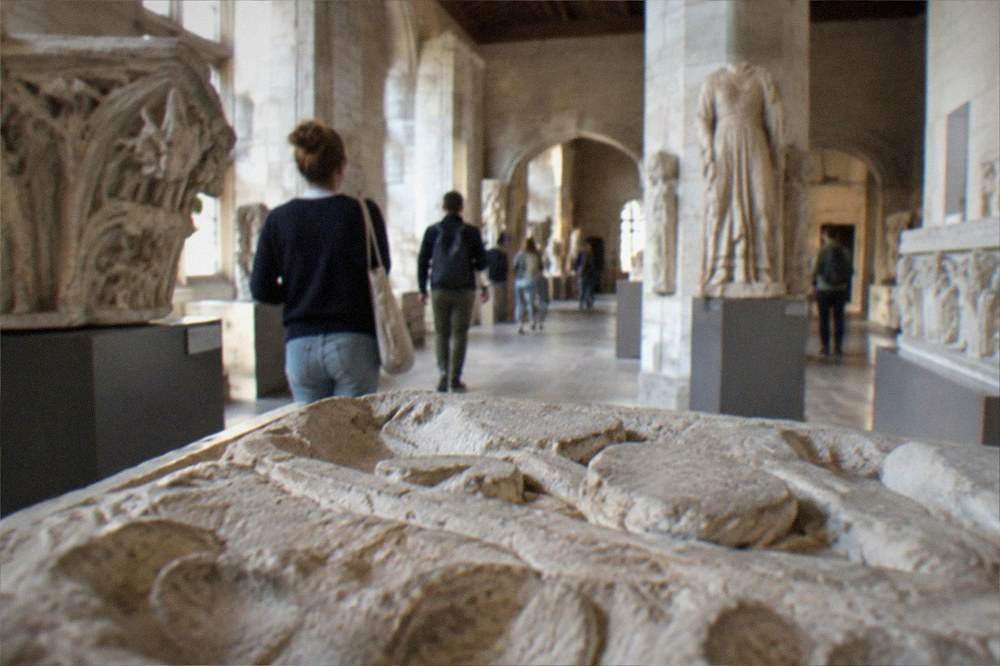 Visitors walking through a museum gallery of stone carvings inside the Chateau des ducs de Bretagne