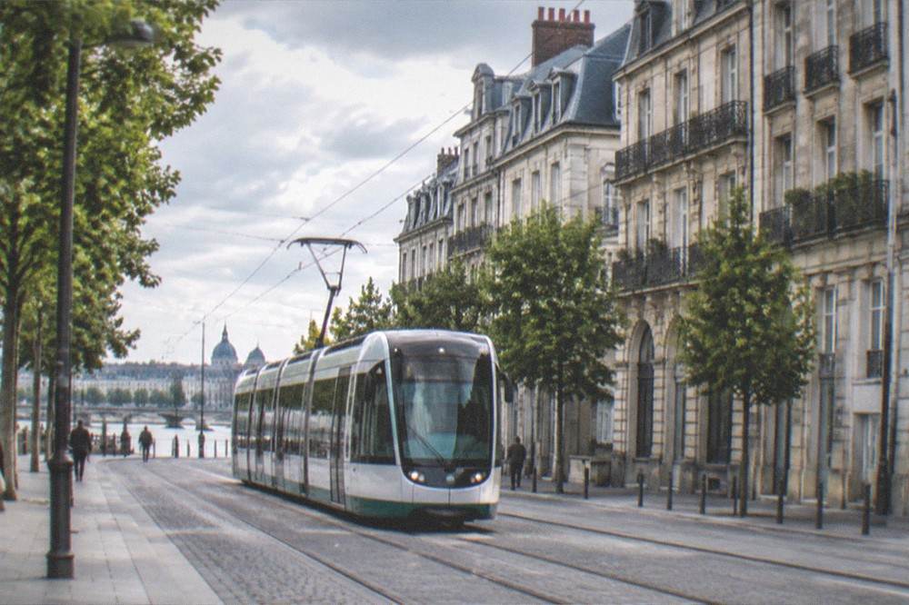 A Nantes tram passing through a city street lined with historic stone buildings