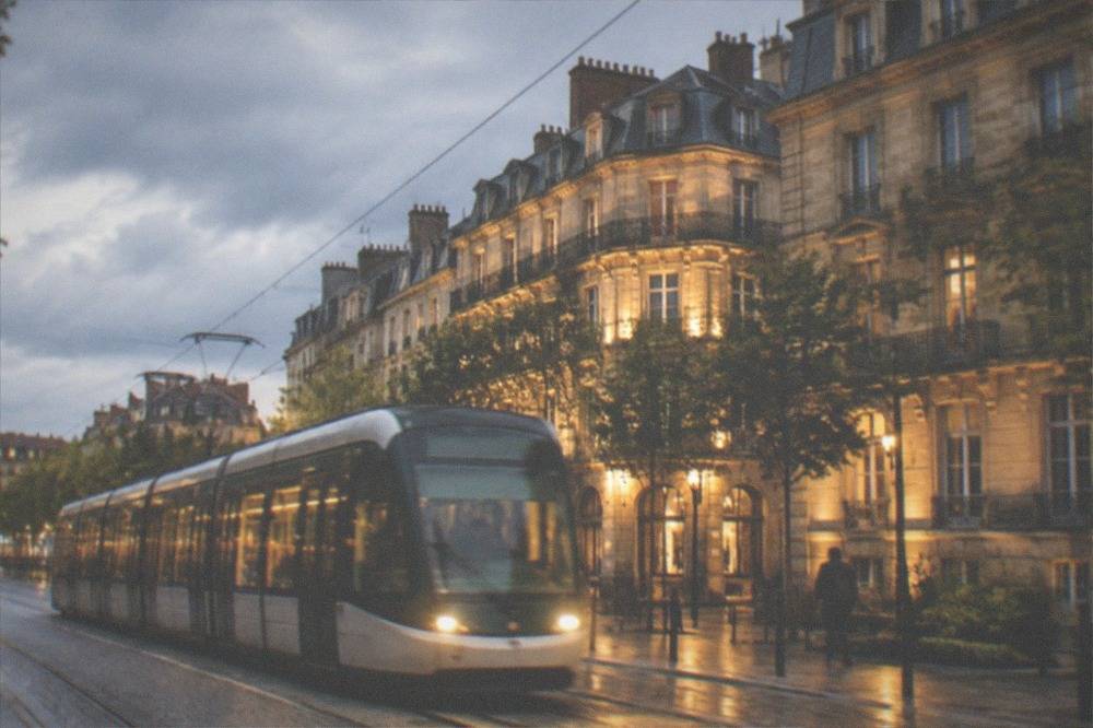 Tram passing illuminated buildings on a Nantes street at night