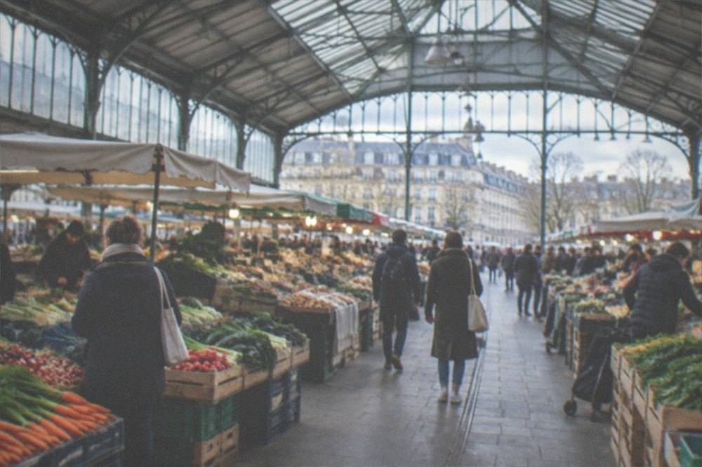 A covered market hall filled with fresh produce stalls and shoppers in Nantes