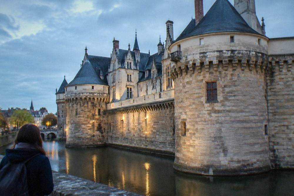 A visitor studying a city map beside the Château des ducs de Bretagne ramparts in Nantes