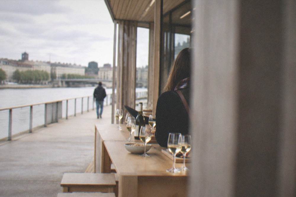 A tasting table with glasses of pale white wine and a bottle in a bright wine room