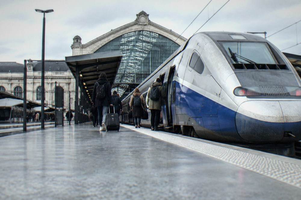 A high-speed train standing at a platform in a French station while passengers board
