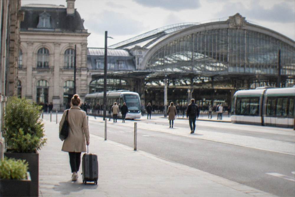 A hotel guest pulling a suitcase along a sunlit city street in the early morning