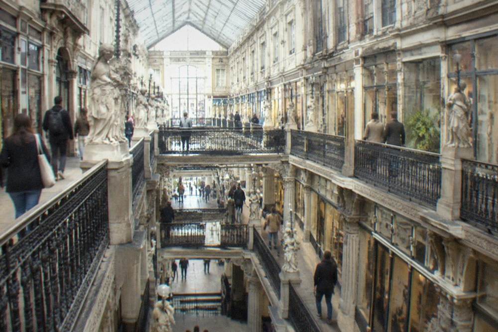 Visitors walking through the Passage Pommeraye shopping gallery with its iron and glass roof