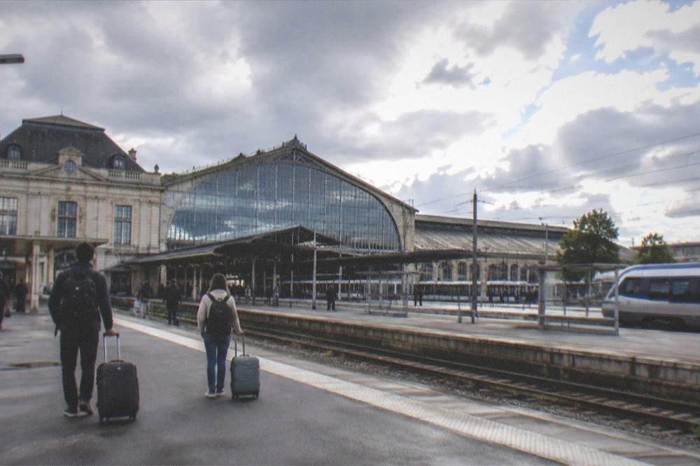 Two travellers with luggage on a regional train platform